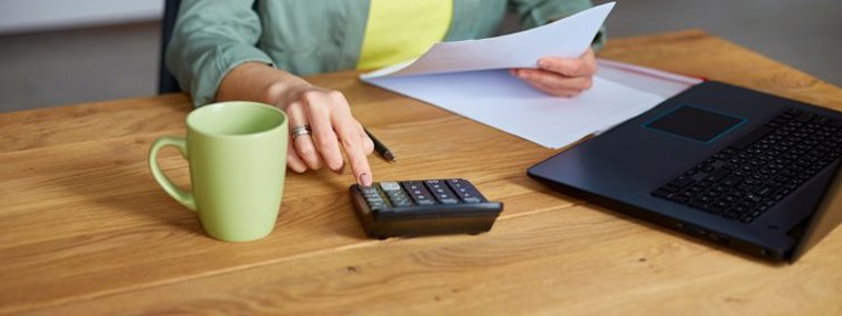 picture of a lady with a laptop, calculator holding paper